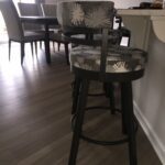 Dark wooden bar stool with patterned cushioned seat and backrest near kitchen counter.