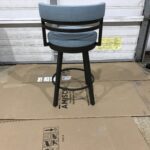 A modern swivel bar stool with a cushioned blue seat and black legs.