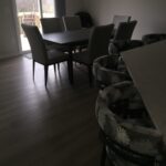 Dimly lit dining area with a modern table and upholstered chairs.