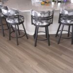 Modern kitchen island with transparent bar stools and wood flooring.